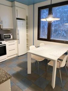 kuchnia z białym stołem i krzesłami oraz oknem w obiekcie PIHLAJISTO 1 - Spacious 4-bedroom condo with patio w Helsinkach