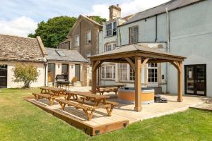 a patio with picnic tables and a gazebo at Historic country house retreat with hot tub, ideal for large groups in Petty France