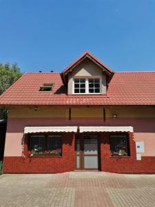 a red brick building with a red roof at Apartament nad wodą 2 in Marzęcino