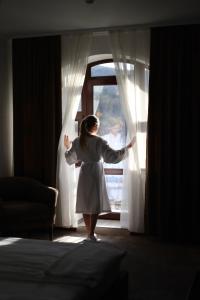 Eine Frau steht vor einem Fenster in der Unterkunft River Stone Hotel in Scheschory