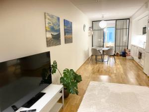 uma sala de estar com um sofá, uma televisão e uma mesa em JATKASAARI-1 Dream stay on Helsinki seafront em Helsinque