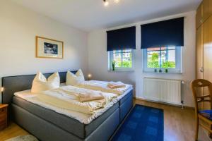 ein Schlafzimmer mit einem Bett und zwei Fenstern in der Unterkunft Ferienhaus Trelleborg Whg. 2 in Sassnitz