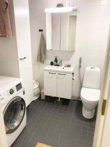 La salle de bains blanche est pourvue de toilettes et d'un lave-linge. dans l'établissement JATKASAARI-1 Dream stay on Helsinki seafront, à Helsinki