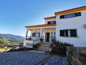 a white house with a staircase and a porch at Casa Colina Troviscainho in Sertã