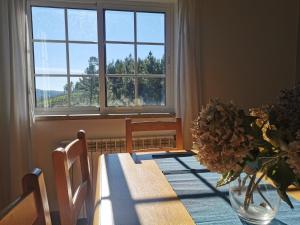 a dining room table with a vase of flowers and a window at Casa Colina Troviscainho in Sertã