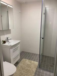 uma casa de banho branca com um lavatório e um chuveiro em LAUTTASAARI Top hideaway in Helsinki em Helsinque