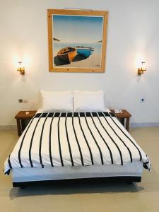 a bedroom with a bed with a painting on the wall at Lazy Inn Kuta Lombok in Kuta Lombok