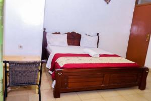 a bedroom with a bed with a red and white comforter at THE PILLAR MOTEL in Kigali