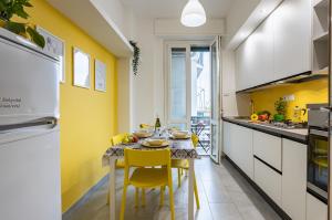 cocina con mesa de comedor y paredes amarillas en Yellowsunny Apartment with Two Balconies, en Pisa