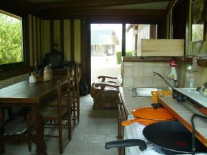a kitchen with a sink and a table with chairs at Chambre chez Corinne in Fourneville