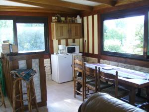 a kitchen with a table and a refrigerator and windows at Chambre chez Corinne in Fourneville