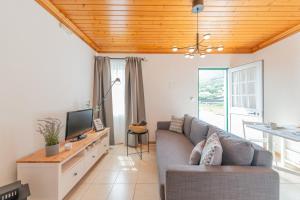 a living room with a couch and a tv at Prainha Apartments in São Roque do Pico