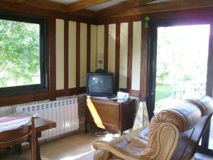 a living room with a tv and a chair at Chambre chez Corinne in Fourneville