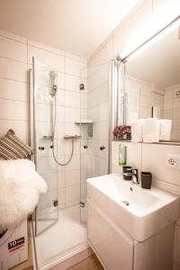 La salle de bains blanche est pourvue d'un lavabo et d'une douche. dans l'établissement Boutique-Appartement Südblick, à Oberstdorf