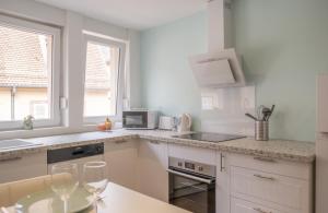 une cuisine avec des placards blancs et une table avec des verres à vin dans l'établissement Nouveau - Entre Terre et Mer - Centre Ville, à Saverne