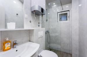 a white bathroom with a toilet and a sink at Apartments Gloria in Budva +31 photos