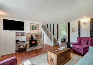 a living room with a couch and a fireplace at Walnut Cottage - Suffolk in Rumburgh