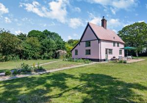 a large white house with a grass yard at Walnut Cottage - Suffolk in Rumburgh