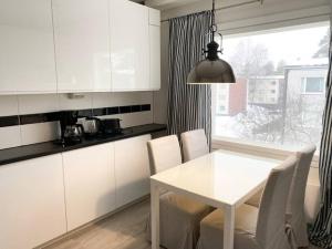 una cocina con armarios blancos y una mesa y sillas blancas. en MELLUNMAKI Renovated 3 bedroom apt next to metro, en Helsinki