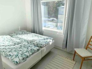 uma cama num quarto com uma janela e uma cadeira em MELLUNMAKI Renovated 3 bedroom apt next to metro em Helsinque