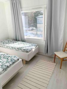 two beds in a room with a window and a chair at MELLUNMAKI Renovated 3 bedroom apt next to metro in Helsinki