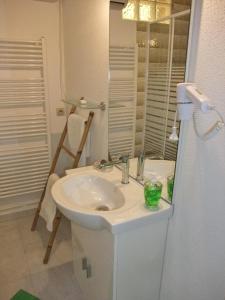 ein weißes Badezimmer mit einem Waschbecken und einem Spiegel in der Unterkunft Gîte Mirabella 