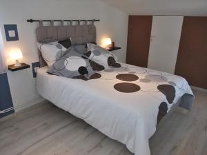ein Bett mit einer braunen und weißen Bettdecke und zwei Lampen in der Unterkunft Gîte Mirabella 