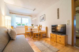 een woonkamer met een tv en een tafel met stoelen bij Burger Elisabeth in Sankt Gallenkirch