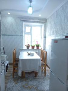 a kitchen with a white table and a window at Dasha Guest House 2 in Naryn