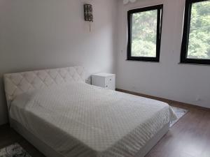 a white bedroom with a bed and two windows at Erme Apart Evler in Dernekpazarı