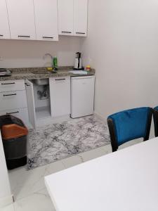 a kitchen with white cabinets and a blue chair at Erme Apart Evler in Dernekpazarı