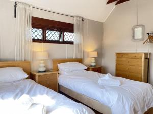a bedroom with two beds and two lamps and a window at Stratton Vow - a true 1920s Arts and Crafts house! in St Ives