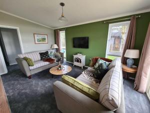 a living room with two couches and a tv at Lodge in beautiful Kent countryside with fine views in Brookland