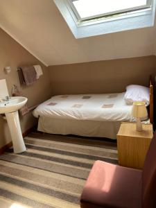 a bedroom with a bed and a sink and a skylight at Belhaven Private Hotel in Aberdeen