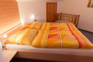 a bed with an orange and yellow blanket on it at Appartement Montanea in Schruns-Tschagguns