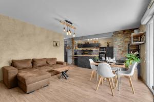 ein Wohnzimmer mit einem Sofa, einem Tisch und Stühlen in der Unterkunft L'Hippocrate - Charmant appartement avec terrasse in Toulouse