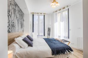 a white bedroom with a large bed with blue pillows at Appartement GRAND CONFORT BORD DE MER Rez-de-Chaussée RESIDENCE LA VAGUE in Houlgate