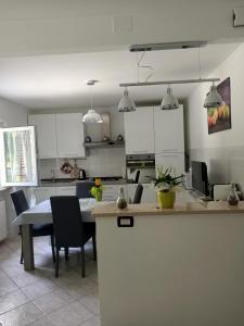 a kitchen with white cabinets and a table and chairs at La casa dei ricordi in Acqualagna