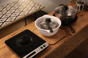 a kitchen counter with a stove and a bowl and a pot at Greenwood Hostel in Izumi-Sano