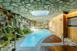 a pool in a house with a stone wall at Le Hameau de mon Père in Manigod