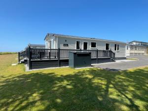 a white house with a large deck and a yard at Holiday Home with Stunning Views in Newquay