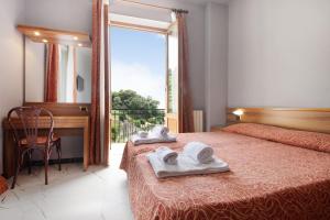 a bedroom with two towels on a bed with a window at Residence Paradiso Bilocale 202 in Moneglia +22 photos