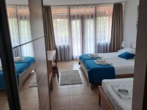 um quarto com 2 camas com lençóis azuis e janelas em Hotel Albamaris em Biograd na Moru
