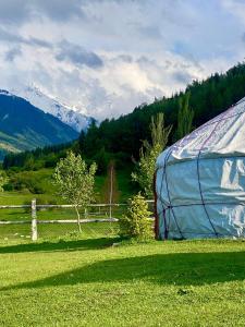 Karakol Yurt Village في كاراكول: خيمة زرقاء في حقل بجانب سياج