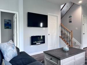 ein Wohnzimmer mit einem Sofa und einem TV an der Wand in der Unterkunft Bell Estates-Brand New Bay View, Beautiful Cottage in North Beach