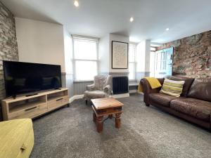 a living room with a couch and a flat screen tv at Treholme, great space for a family beach holiday! in St Ives