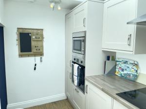 a kitchen with white cabinets and a counter top at Treholme, great space for a family beach holiday! in St Ives