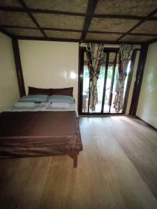 een slaapkamer met een bed in een kamer met ramen bij Tony's Country Glamping with chalet with private wash room accommodation in El Nido