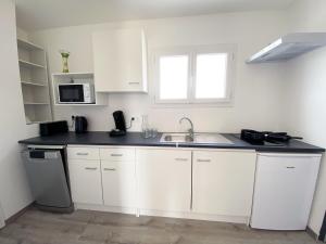 a white kitchen with a sink and a microwave at Auberge des Plaines - Appart'hôtel in Arles