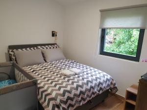 1 dormitorio con cama con edredón y ventana en Apartmani Višegradski pogled, en Višegrad